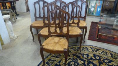 trois chaises en bois posées sur un tapis bleu dans une pièce