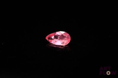 a close up of a pink diamond on a black surface
