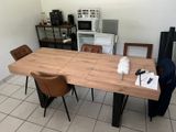 a wooden table with chairs and a microwave in the background