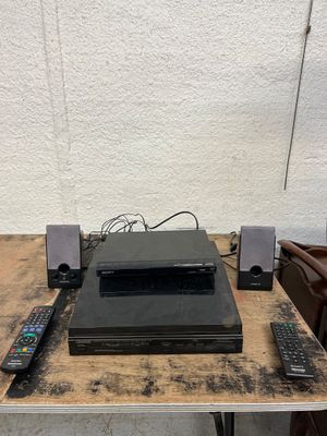 Sur la table se trouvent une télécommande, un lecteur DVD et d'autres appareils électroniques