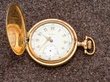 une montre de poche en or posée sur un tissu marron
