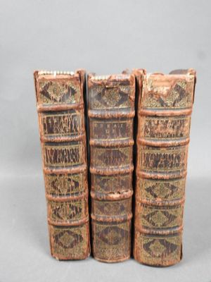 three old books are stacked on top of each other on a table