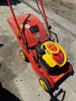 une tondeuse à gazon rouge et jaune posée sur le trottoir