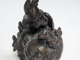a statue of a rooster sitting on top of a rock