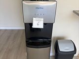 un distributeur d'eau placé à côté d'une poubelle