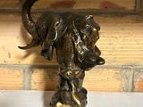 statue of an elephant on a rock on a table in front of a brick wall