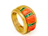 un gros plan d'une bague en or sertie de pierres orange et vertes