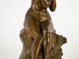 une photo d'une statue en bronze représentant une femme assise sur une souche d'arbre