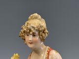 une figurine représentant une femme tenant une fleur à la main
