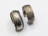 two silver rings with engraved designs on them on a white surface