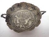 a silver bowl with a design on it on a white surface