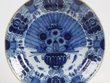 une assiette bleue et blanche sur laquelle est représenté un crâne