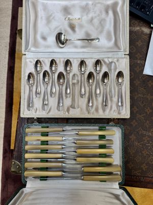 de nombreuses cuillères et fourchettes dans un coffret posé sur une table
