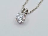 a close up of a diamond necklace on a white surface