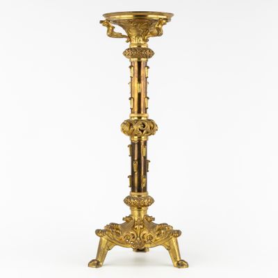 a gold plated candle holder with a candle on a stand