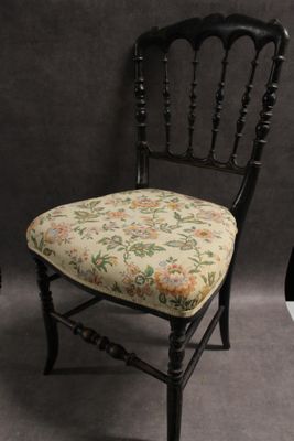 une chaise noire sur laquelle est posé un coussin d'assise à motifs floraux
