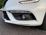the front end of a white car with its lights on