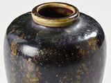a black vase with a brown rim sitting on a white surface