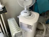 un ventilateur blanc posé sur une table à côté d'un radiateur