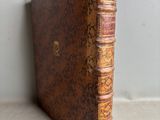 un vieux livre posé sur une table à côté d'un mur