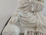 a statue of a man sitting on a table with a book