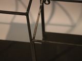 a metal table with a glass top on a black floor