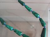 necklace made of green and blue glass beads with a blue bead