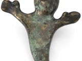 une ancienne figurine en bronze représentant un homme les bras tendus