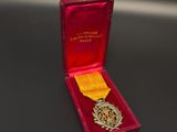 médaille dans un écrin rouge posé sur un fond noir, ornée d'une étoile dorée