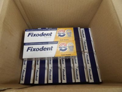 plusieurs boîtes de dentifrice Fixodent rangées dans un carton