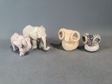 trois petites figurines représentant des éléphants et une girafe, posées sur une surface grise