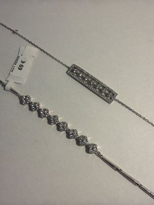 deux colliers en argent posés sur une table blanche, avec une étiquette de prix