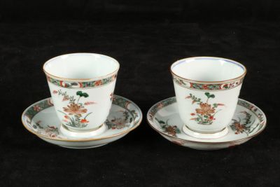 pair of cups and saucers with floral designs on them on a black background