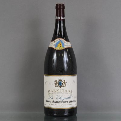 une vieille bouteille de vin posée sur une table en verre