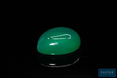 une image représentant une pierre de jade verte posée sur une surface noire