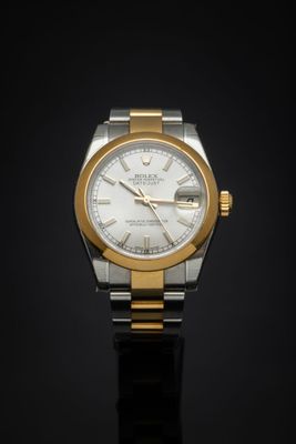 a close up of a watch on a black surface with a black background
