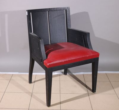 a black chair with a red leather seat on a tile floor