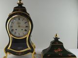 une horloge noire et dorée posée à côté d'une autre horloge noire et dorée