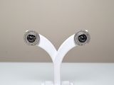 une paire de boucles d'oreilles à clous ornées de diamants noirs et blancs, présentées sur un socle blanc
