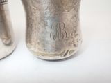 a silver cup with a monogram on it next to a silver cup with a monogram on it