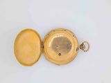 an open gold pocket watch sitting on top of a white surface