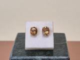 a close up of a pair of gold earrings on a marble block