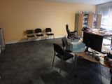 a room with a desk, chairs, and a computer monitor