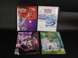 Quatre cartes Pokémon sont posées les unes à côté des autres sur une surface noire.
