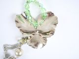 a silver flower brooch with green beads and a pearl bead