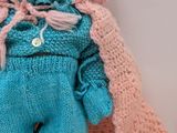 a baby doll that is wearing a blue and pink outfit
