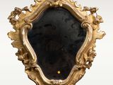 un miroir ancien à cadre doré, orné de fleurs et de feuilles sur fond blanc