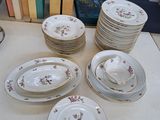 de nombreuses assiettes et tasses posées sur une table où se trouvent des livres