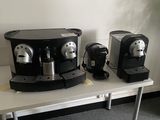 trois machines à café posées sur une table à côté d'une plante