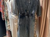 une combinaison en jean dans un magasin où des vêtements sont suspendus à un portemanteau